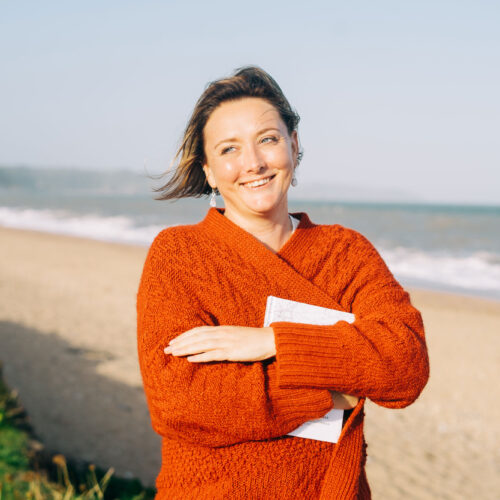 Claire Collis Writer and Digital Education Specialist stood on a beach