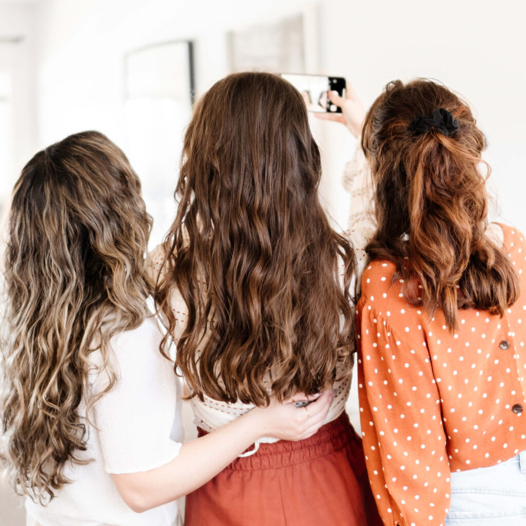 Three white women with long brown hair taking a selfie