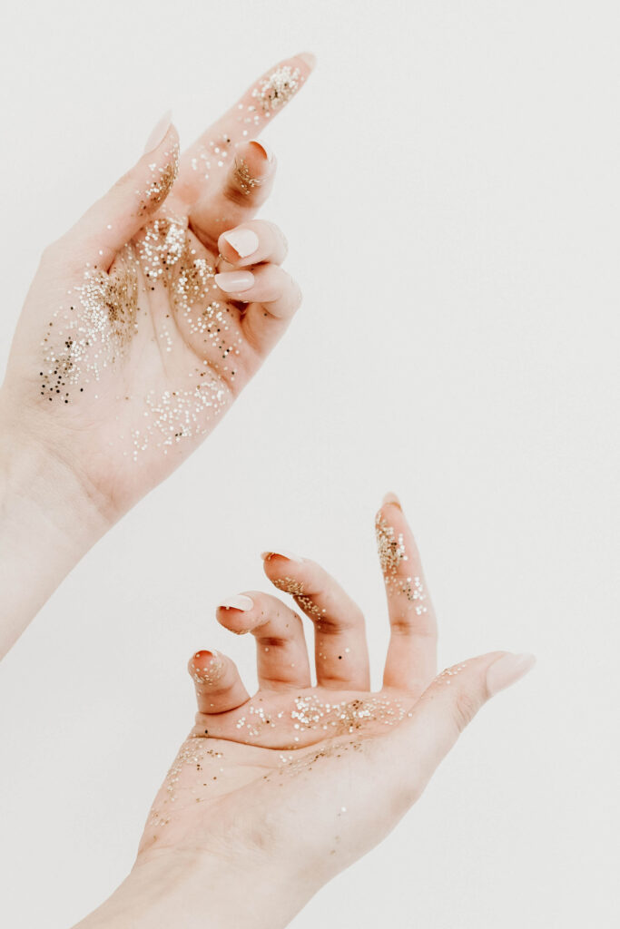 Two hands of a white woman covered in glitter
